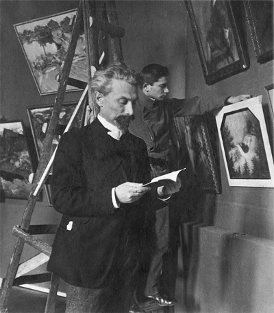 1911 Leonid and his son Alexander, preparing for the Union of Russian Artists' Spring Exhibition. Alexander is hanging his father’s picture of Tolstoy on his deathbed.